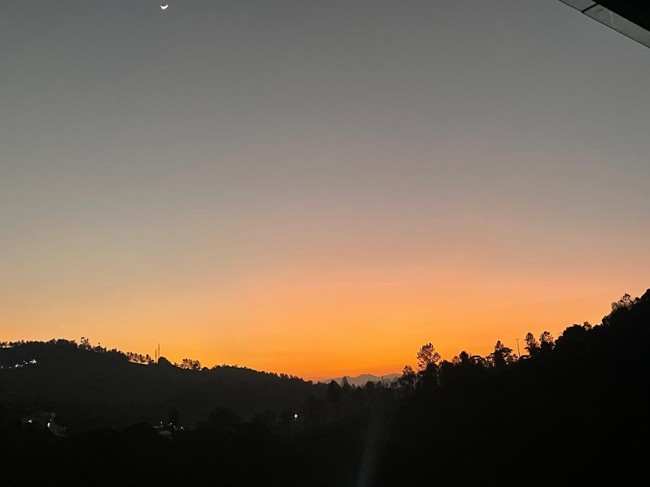 Golden sunset with crescent moon over the valley